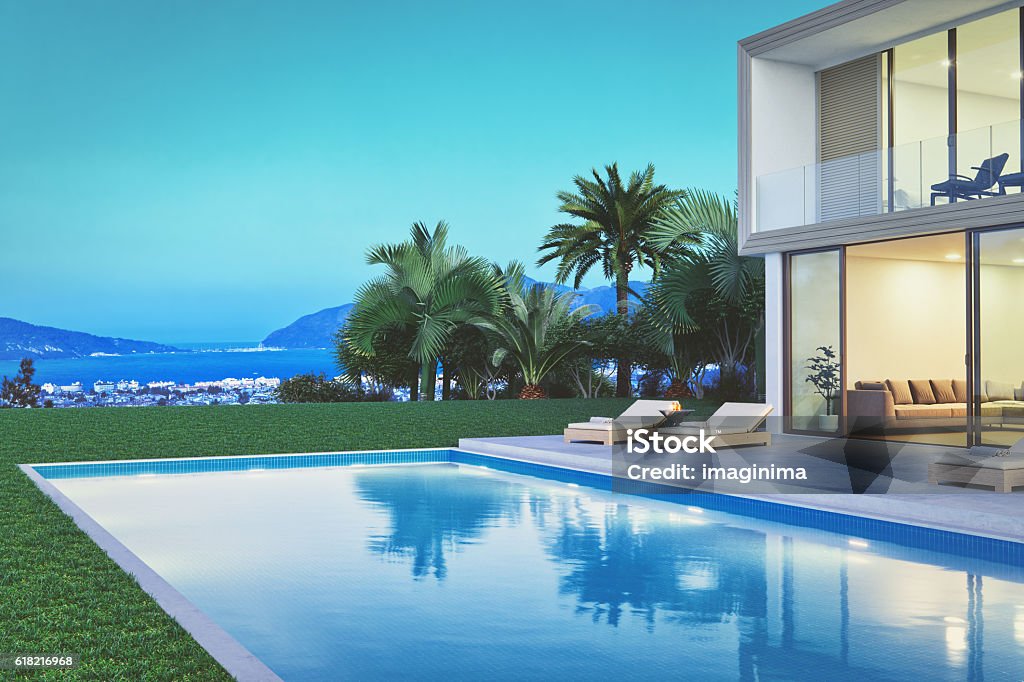 Modern Luxury Villa With Pool At Dawn Modern villa exterior with pool and beautiful view at dawn. Sea Stock Photo