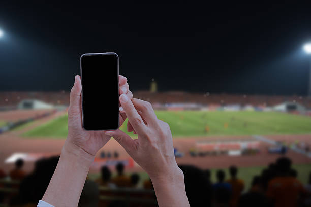 istock Hand holding mobile smart phone with black screen, blurred socce 618315440