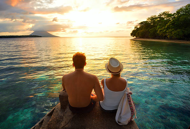 feliz pareja en el muelle en el fondo colorido atardecer - honeymoon fotografías e imágenes de stock