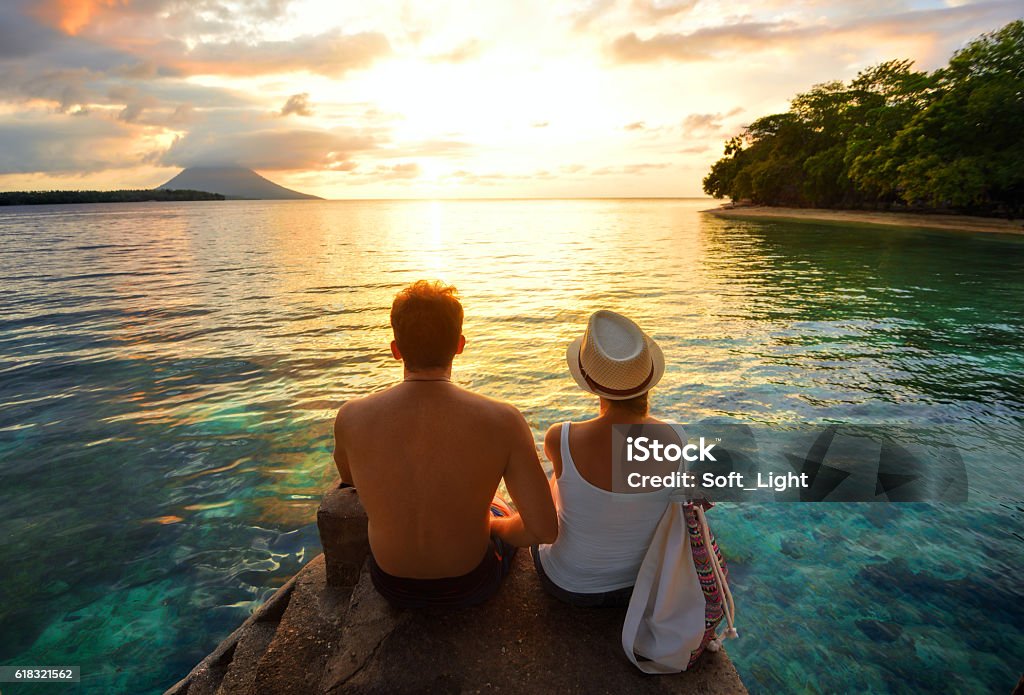 Happy couple on the pier on background colorful sunset Romantic couple on the beach at colorful sunset on background Travel Stock Photo