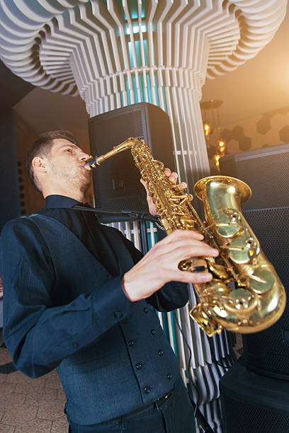 istock Young man plays a musical instrument saxophone 618323116