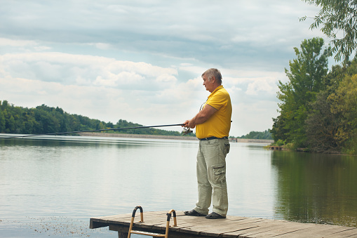 Senior man fishing and relaxing on a calm river