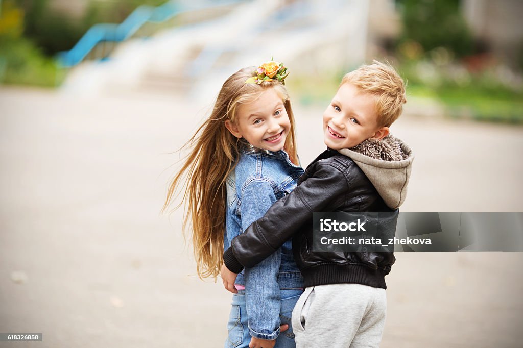 Portrait of a happy children - boy and girl City style. Urban kids. Portrait of two happy children - boy and girl. Brother and sister hugging. School holidays concept. The first children's love Boys Stock Photo