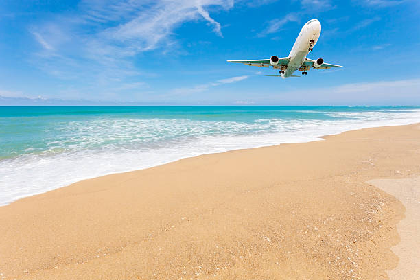 istock Airplane landing above beautiful beach and sea background. 618331550