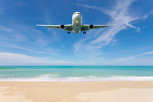 istock Airplane landing above beautiful beach and sea background. 618332962