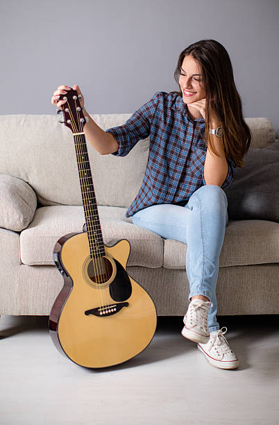 istock Young woman on sofa holding guitar 618334734