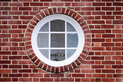 Round window in a brick wall with white frame