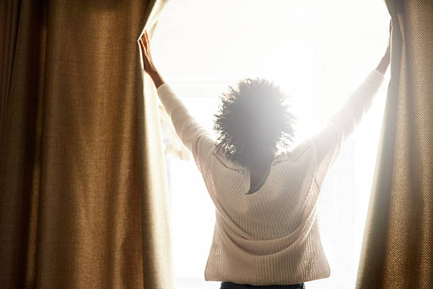 New day, new possibilities Rearview shot of a woman opening the curtains on a bright sunny day morning stock pictures, royalty-free photos & images