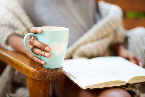 Tea and a good book. What more do you need? Cropped shot of a woman relaxing with a book and a cup of coffee cup of tea hands stock pictures, royalty-free photos & images