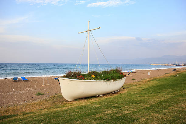 view of the promenade in the seaside town, in the middle of the roundabout old fishing boat, a hot day