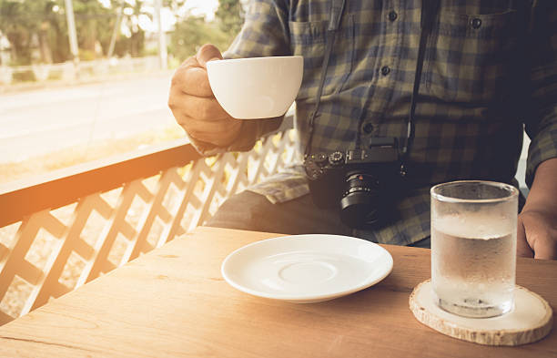 Man holding coffee and drinking water with camera vintage tone.
