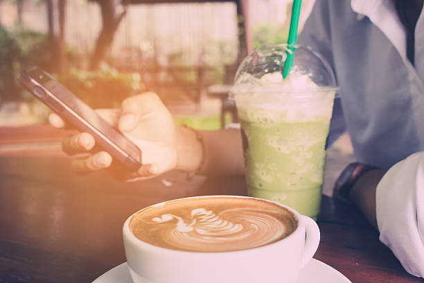 istock Women use mobile phone and drink green tea vintage tone. 618344908