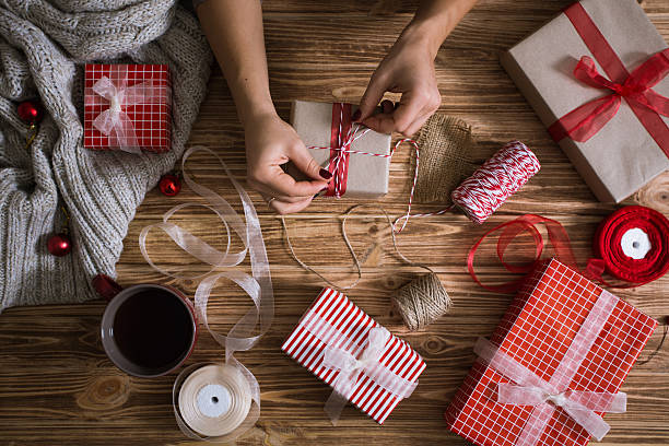 istock Female hands wrapping Christmas presents in paper and tying them 618345738