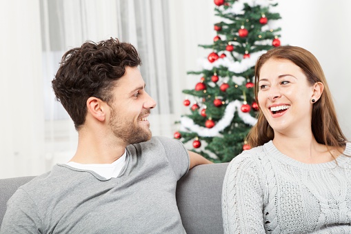 christmas couple is happy and laugh in front of white background and christmas tree