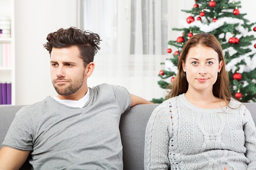 young modern couple is irritated of christmas with christmas tree in background