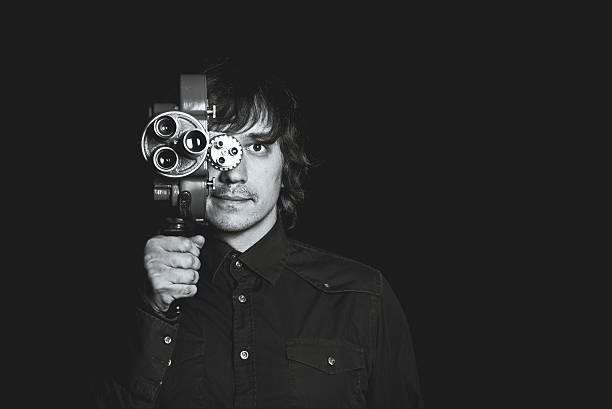 istock Guy takes on a retro movie camera. Black and 618348582