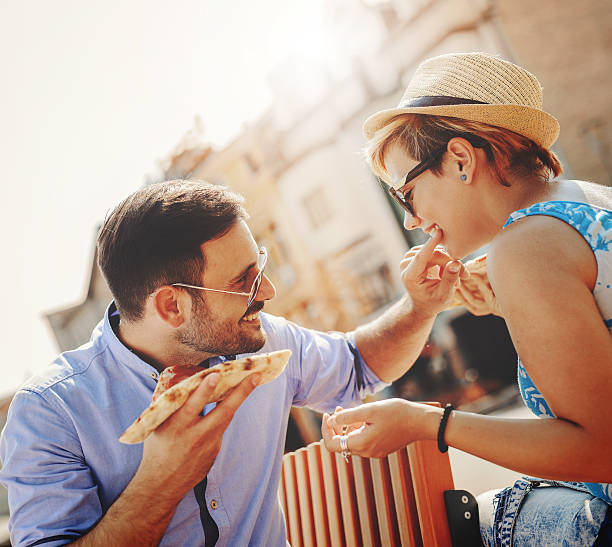 istock Couple eating pizza outdoors and smiling 618349772