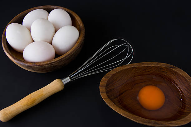istock White Egg in wooden teak bowl whisk on black background 618355020