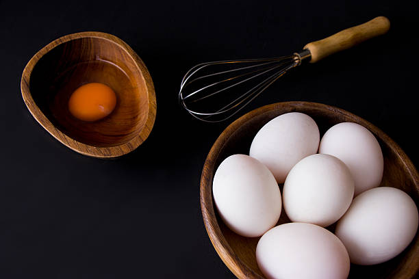 istock White Egg in wooden teak bowl whisk on black background 618355076