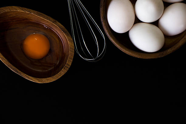 istock White Egg in wooden teak bowl whisk on black background 618355084