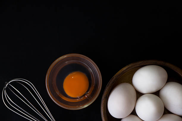istock White Egg in wooden teak bowl whisk on black background 618355238