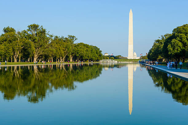 Reflection of in pool of Washington Monument, Washington, DC Washington DC, USA - October 16, 2016: Washington Monument in Washington, DC with its reflectio in the reflecting pool.  Tourists can be seen walking around the grounds on a beautiful clear day. washington monument reflecting pool stock pictures, royalty-free photos & images