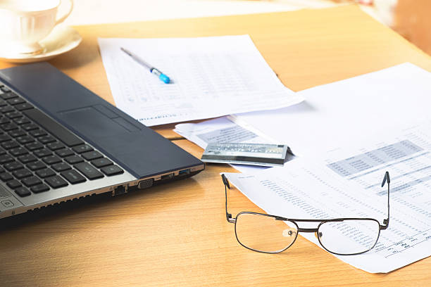 istock spectacles with turnover graph paper Laptop on wood desk. vintag 618358044