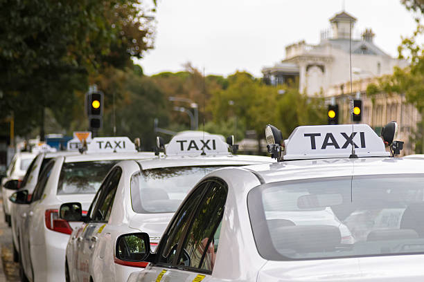 białe taksówki parkujące wzdłuż chodnika w adelajdzie, australia - taxi zdjęcia i obrazy z banku zdjęć