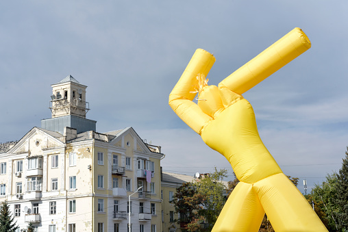 yellow inflatable man against the sky and the city on holiday