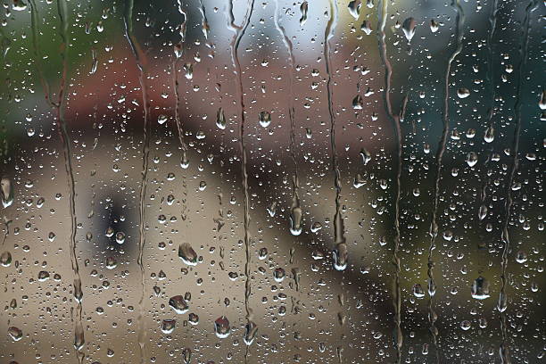 istock Rain drops on window with house and church in background 618424392