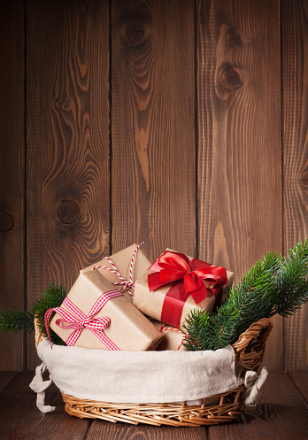 Christmas gift boxes and fir tree branch in basket on wooden table. View with copy space