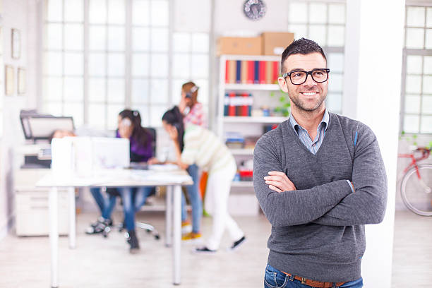 istock Smiling young man standing arms crossed in workplace 618431028