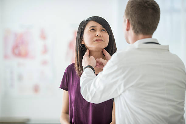 Thyroid Cancer Checkup A woman is at the doctor's office for a visit to her doctor. She is getting a medical examination and advice for her health. Here she receives a thyroid examination for a cancer check. thyroid gland stock pictures, royalty-free photos & images