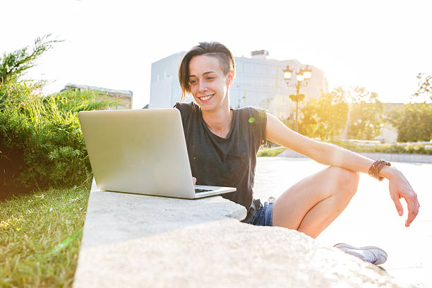 istock Smiling woman using laptop in the city. 618441320