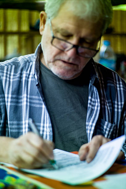 istock Elderly man with glasses signing a text on paper 618441376