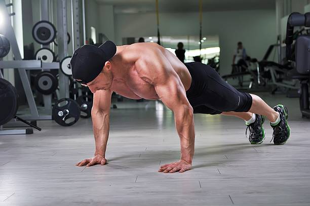 istock Handsome powerful athletic man performing push ups at the gym. 618444630