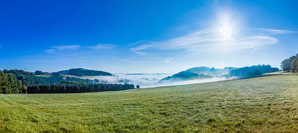 foggy rural landscape in morning in the eifel with blue sky