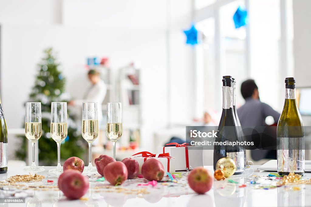 Table with alcoholic drinks and fruits Full champagne flutes, apples, Christmas presents on table in office Office Party Stock Photo