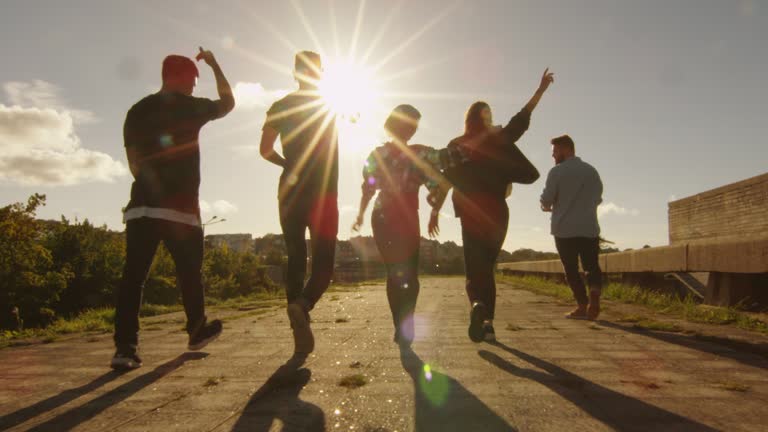 Group of Happy Teenagers Laughing, Raising Hands, Jumping While Moving Outwards Camera.