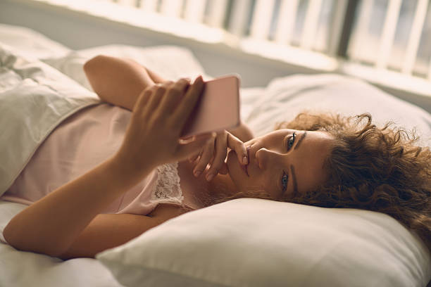 istock Young beautiful woman with her phone in the bed 618512880