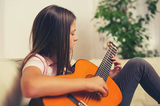 istock Cute little girl practicing her guitar lessons at home 618514516