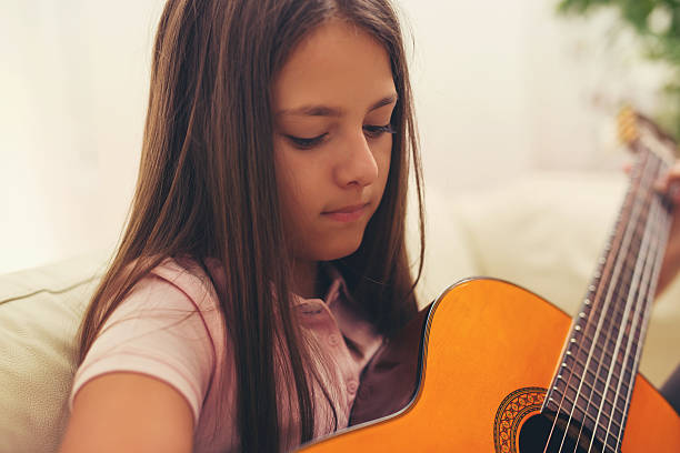 istock Cute little girl practicing her guitar lessons at home 618514762