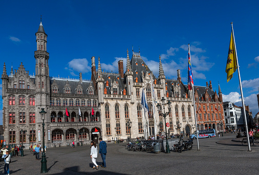 brugge, belgium - July 3, 2016: People are walking around historical gothic buildings at market place in brugge belgium