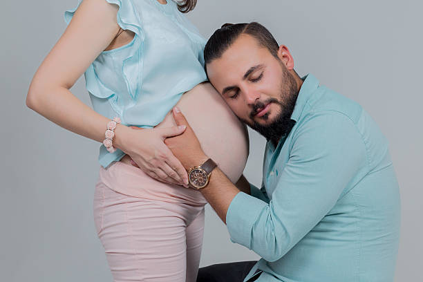 embarazo mujer y hombre escuchando a su creciente de vientre - human pregnancy flash fotografías e imágenes de stock