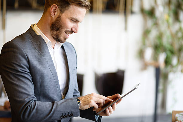 istock Young businessman using digital tablet in office building hallway. 618524410