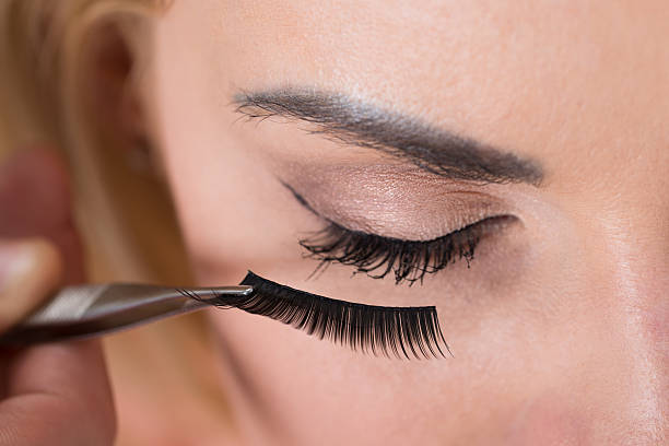 False Eyelashes Being Put On Woman's Eye Close-up of false eyelashes being put on woman's eye false lashes stock pictures, royalty-free photos & images