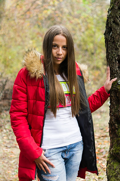 istock Young woman alone on a forest wearing  red overcoat 618534240