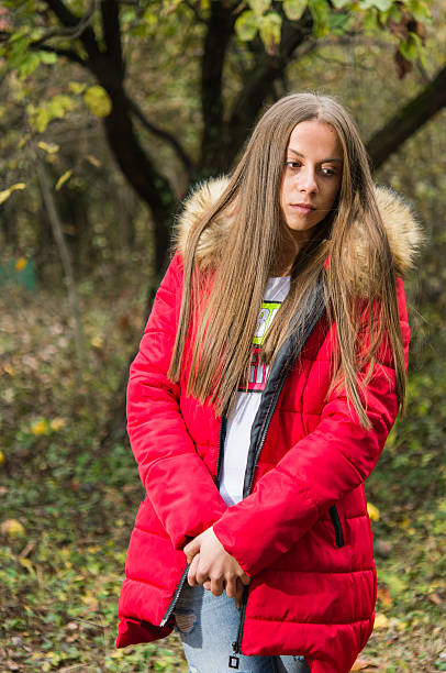 istock Young woman alone on a forest wearing  red overcoat 618534296