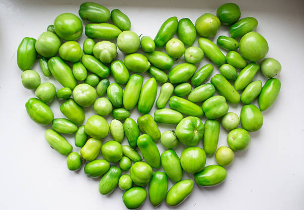 Shape heart of green tomatoes on white background