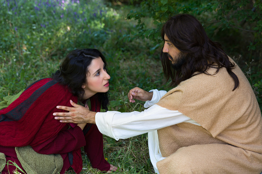 Repentant sinner woman touching the robe of Jesus, asking for forgiveness and healing